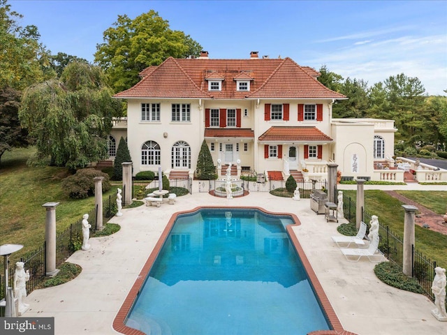 back of house featuring a fenced in pool, a tiled roof, fence private yard, and a patio