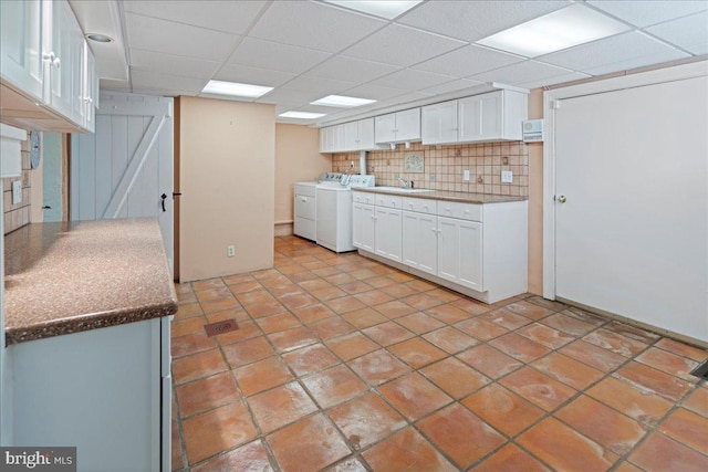 kitchen featuring white cabinetry, washing machine and dryer, tasteful backsplash, and a sink