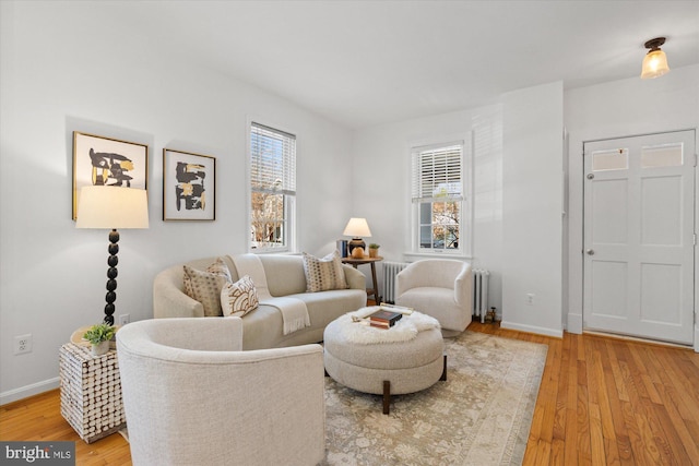 living area with light wood-style flooring, radiator, and baseboards