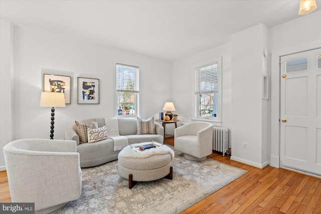 living room featuring radiator heating unit, baseboards, and wood finished floors