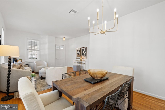 dining space with visible vents, baseboards, radiator heating unit, and light wood finished floors