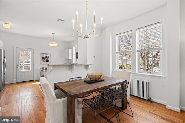 dining room with visible vents, radiator, light wood-type flooring, and baseboards