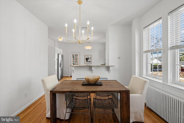 dining area featuring visible vents, baseboards, radiator heating unit, and light wood-style floors