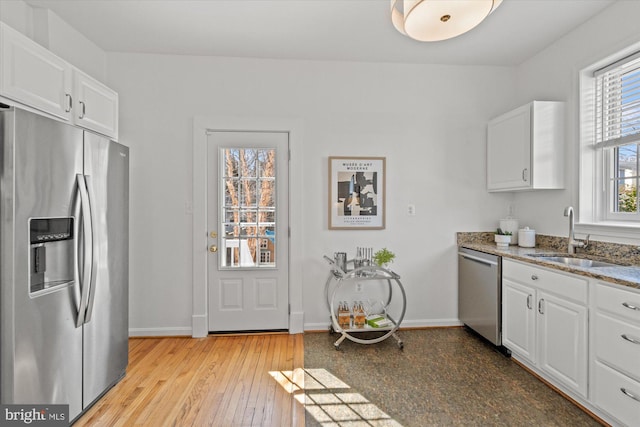 kitchen with a sink, stone countertops, white cabinetry, and stainless steel appliances