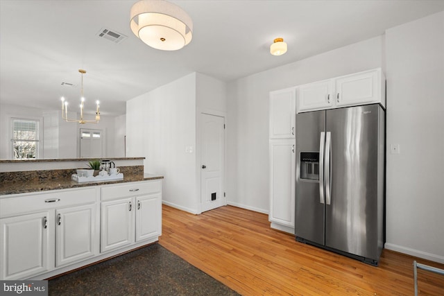 kitchen featuring visible vents, baseboards, stainless steel fridge with ice dispenser, and white cabinetry