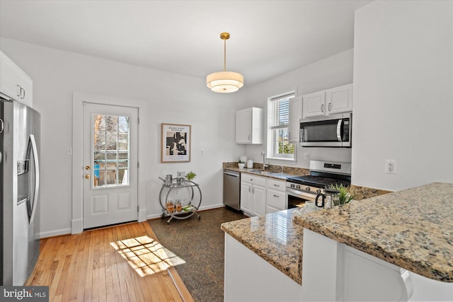 kitchen with light stone counters, white cabinets, appliances with stainless steel finishes, and a sink