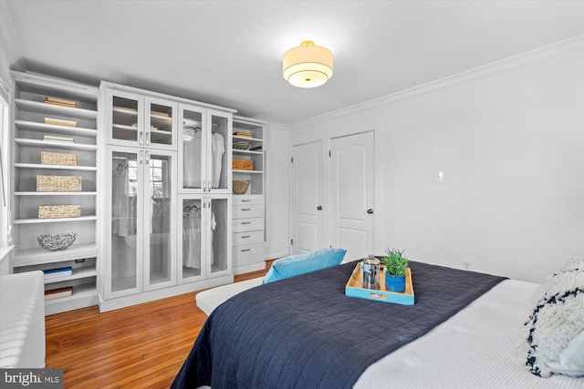 bedroom with wood finished floors and ornamental molding