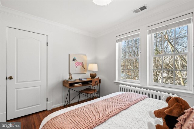 bedroom with visible vents, radiator, baseboards, ornamental molding, and wood finished floors