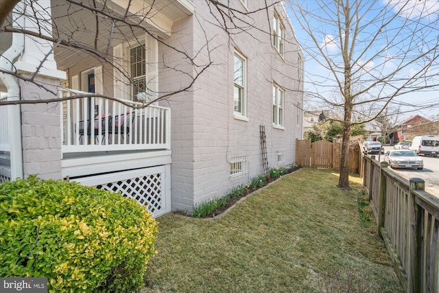 view of side of property with concrete block siding, a lawn, and fence