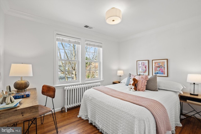 bedroom featuring visible vents, crown molding, radiator heating unit, and hardwood / wood-style flooring