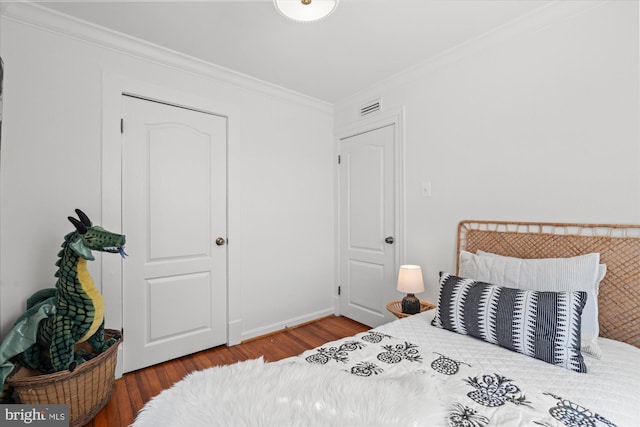 bedroom featuring visible vents, crown molding, baseboards, and wood finished floors