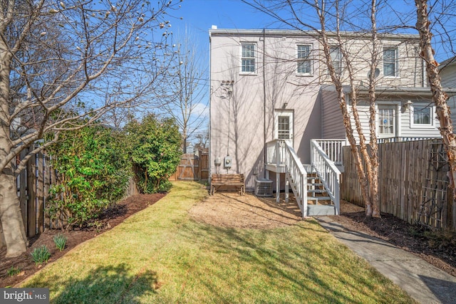 rear view of house featuring a fenced backyard and a lawn