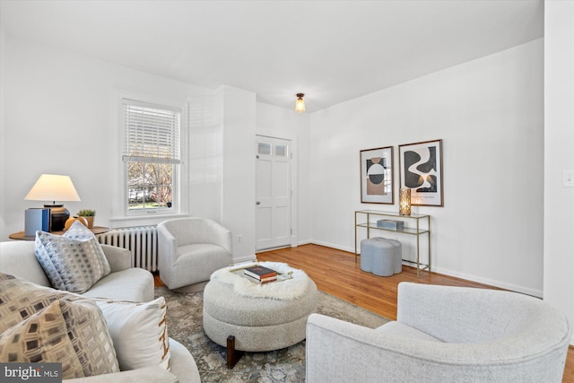 living area with radiator heating unit, wood finished floors, and baseboards