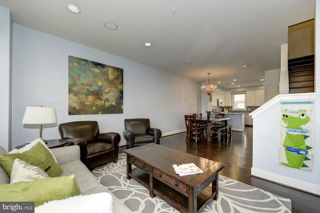 living room featuring stairs, dark wood-type flooring, a notable chandelier, and recessed lighting