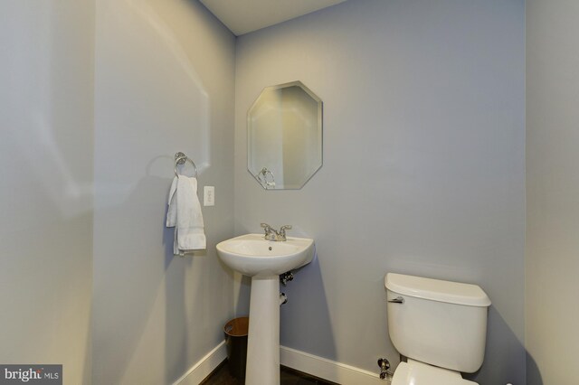 half bath featuring baseboards and toilet