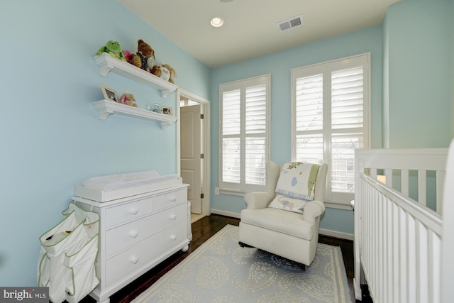 bedroom featuring visible vents, a crib, dark wood-style floors, recessed lighting, and baseboards