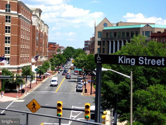 view of street featuring sidewalks, curbs, traffic lights, and street lighting