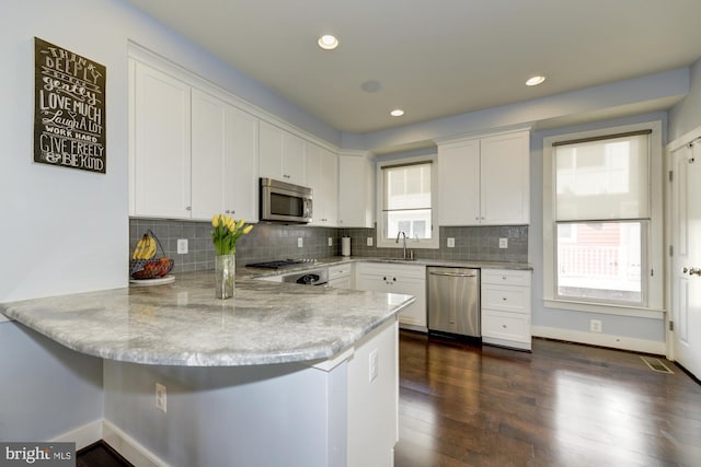 kitchen featuring white cabinetry, a peninsula, decorative backsplash, and stainless steel appliances