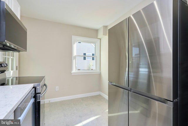 kitchen with light stone countertops, baseboards, and stainless steel appliances