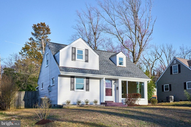 cape cod house with central air condition unit, fence, a front yard, and a shingled roof