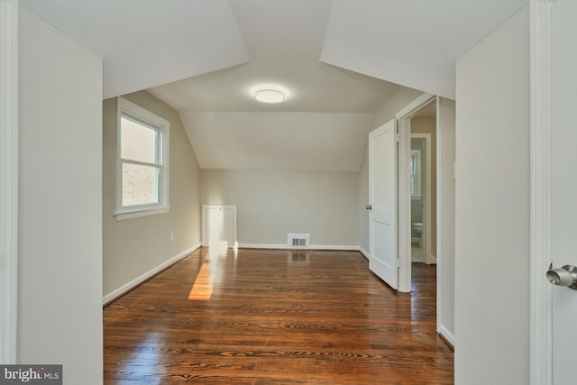 bonus room featuring lofted ceiling, baseboards, visible vents, and dark wood-type flooring