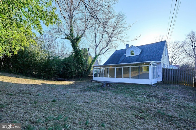 exterior space featuring fence, a yard, roof with shingles, a sunroom, and a chimney