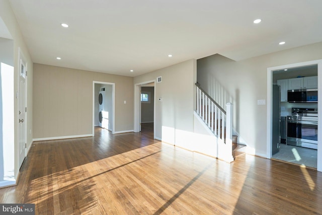 unfurnished living room with stairs, recessed lighting, wood finished floors, and baseboards