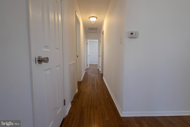 hall with visible vents, baseboards, and dark wood finished floors