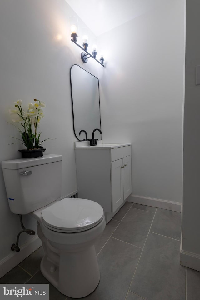 half bath with baseboards, toilet, vanity, and tile patterned flooring