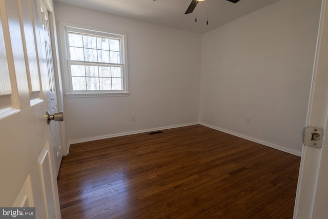 spare room featuring ceiling fan, dark wood-type flooring, and baseboards