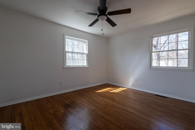 empty room with visible vents, baseboards, dark wood-type flooring, and a ceiling fan