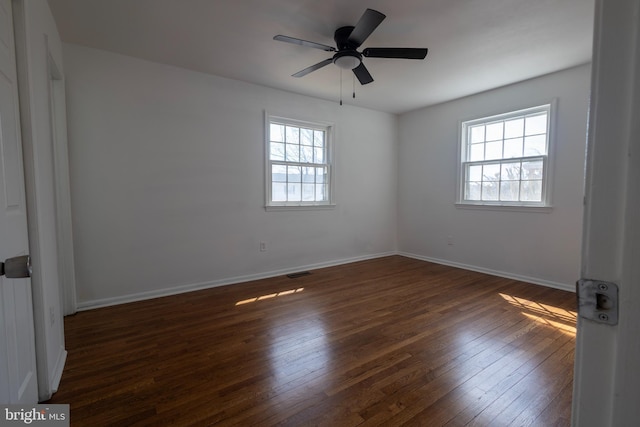 spare room featuring hardwood / wood-style floors, a healthy amount of sunlight, visible vents, and baseboards