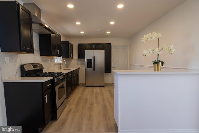 kitchen with a sink, stainless steel appliances, light countertops, dark cabinets, and backsplash