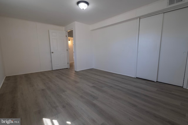 unfurnished bedroom with a closet, visible vents, and wood finished floors