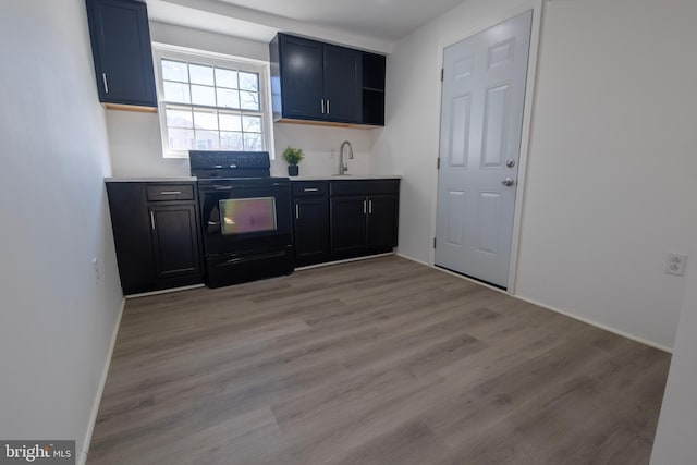 kitchen with light wood finished floors, open shelves, black / electric stove, light countertops, and baseboards