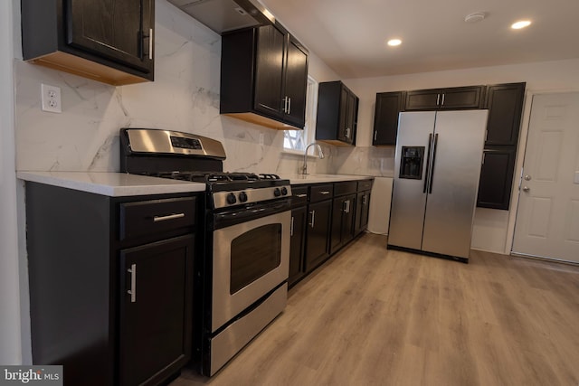 kitchen featuring a sink, tasteful backsplash, stainless steel appliances, light wood finished floors, and light countertops