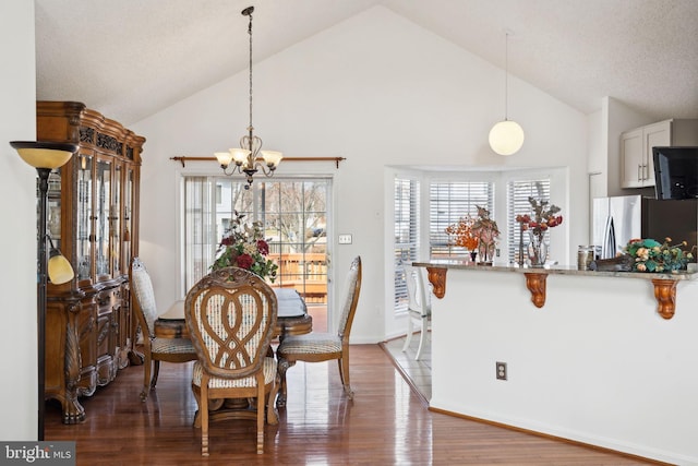 dining room with a textured ceiling, an inviting chandelier, wood finished floors, and high vaulted ceiling