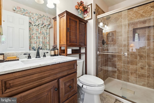 full bathroom featuring vanity, a shower stall, toilet, and a textured ceiling