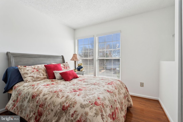 bedroom featuring a textured ceiling, baseboards, and wood finished floors