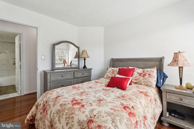 bedroom with ensuite bath, a textured ceiling, and wood finished floors