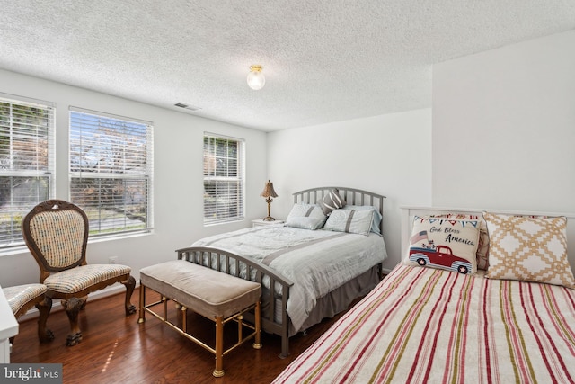 bedroom featuring wood finished floors, visible vents, and a textured ceiling