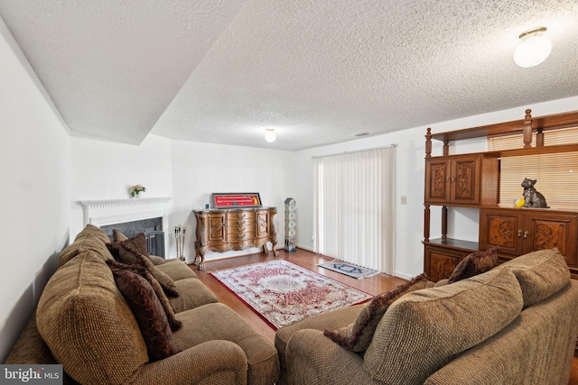 living area featuring visible vents, a fireplace, a textured ceiling, and wood finished floors