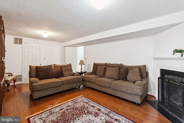 living room with visible vents, a fireplace, a textured ceiling, and hardwood / wood-style flooring