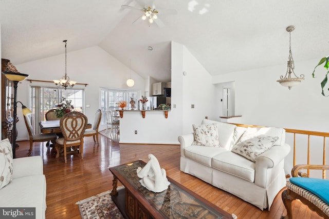 living area featuring vaulted ceiling, ceiling fan with notable chandelier, and hardwood / wood-style floors