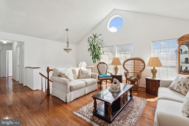 living area featuring baseboards, wood-type flooring, a textured ceiling, and high vaulted ceiling