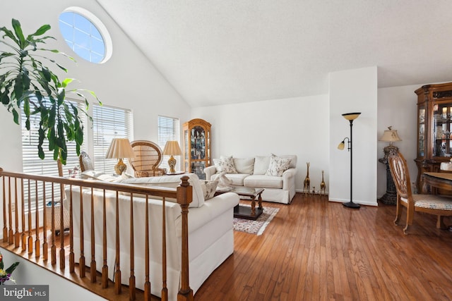 living room with hardwood / wood-style flooring, baseboards, and high vaulted ceiling