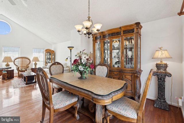 dining space with baseboards, lofted ceiling, an inviting chandelier, and wood finished floors