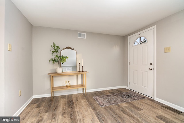 foyer with wood finished floors, visible vents, and baseboards