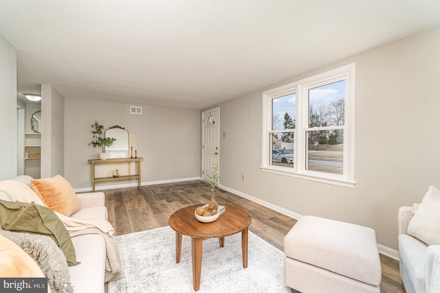 living room with visible vents, baseboards, and wood finished floors