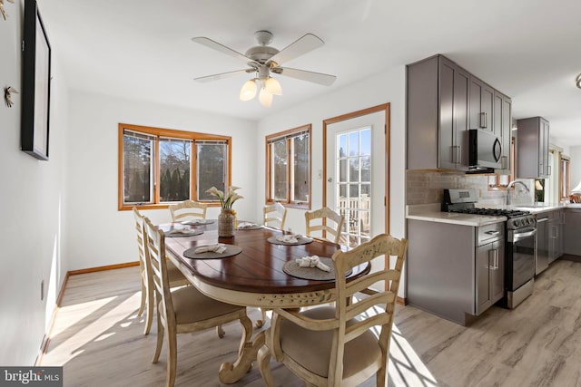 dining room featuring baseboards, a ceiling fan, and light wood finished floors